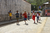 A group of african american kids run on a cobblestone side street, participating on a spoon and egg race. Portobello, Colón, Panama, Central America - photo by H.Olarte